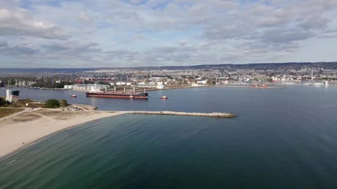 A massive cargo ship bulk carrier leaves the seaport, accompanied by tugboats Stock Footage 255653381