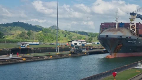 A massive cargo ship navigates the historic Panama Canal locks, assisted by Stock Footage 346791703