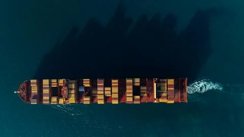 Massive Cargo Ship Transporting Multi-colored Containers Across Deep Blue O.. Stock Photos
