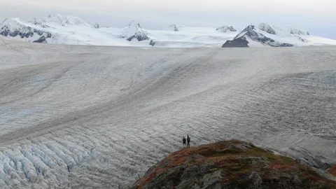 Massive Cinematic Glacier Behind Two Hikers | Alaska Aerial Signature Series Stock Footage 97722100