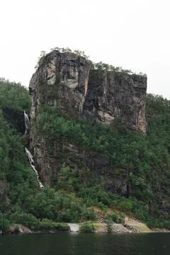 Massive cliff with forest and side waterfall in fjord near Bergen, Norway Stock Photos