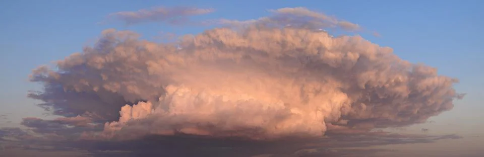 Massive cloud dominates the sky. Pink and white hues glow from the top. Clear 写真素材