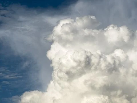 Massive cloud formation rises with dramatic light against blue sky. Voluminou 스톡 사진