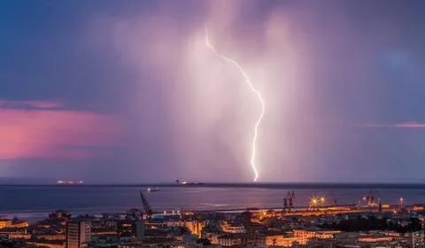 Massive cloud to ground lightning bolts hitting the horizon of city lights Stock Photos