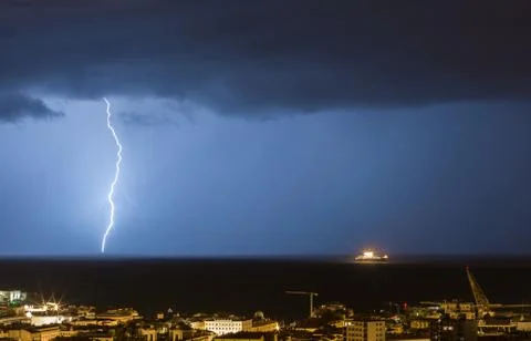 Massive cloud to ground lightning bolts hitting the horizon of city lights Stock Photos