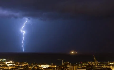 Massive cloud to ground lightning bolts hitting the horizon of city lights Stock Photos