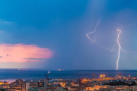 Massive cloud to ground lightning bolts hitting the horizon of city lights Stock Photos