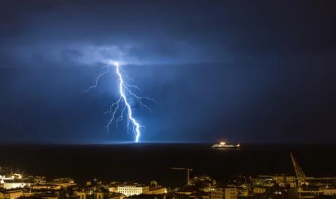 Massive cloud to ground lightning bolts hitting the horizon of city lights Stock Photos