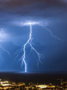 Massive cloud to ground lightning bolts hitting the horizon of city lights Stock Photos