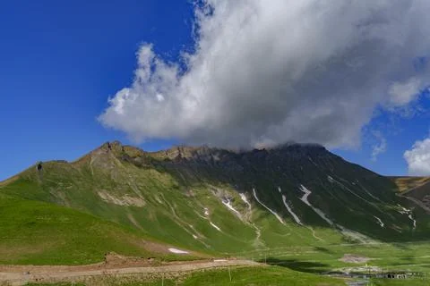 Massive cloud over rugged green Caucasus mountain slope in Georgia Stock Photos