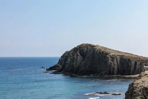 Massive coastal cliffs rising from calm mirror-like Mediterranean sea Stockfoto's