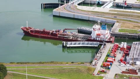 Massive commercial ship navigates emerald waters flanked by grassy banks Vídeos de archivo 327649560