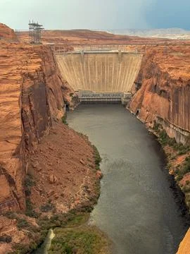 Massive concrete dam built between red canyon cliffs with river flowing below Foto stock