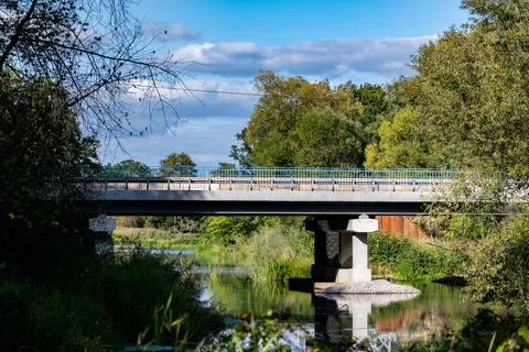 Massive concrete road bridge spanning across a peaceful river Stockfoto's