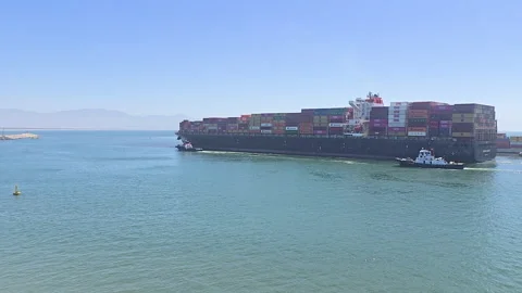 Massive container vessel maneuvering into Ensenada port in Mexico with tugboat Видео 331072397