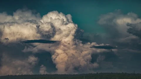 Massive cumulonimbus cloud building and morphing against vibrant teal backdrop Stock Footage 317531692