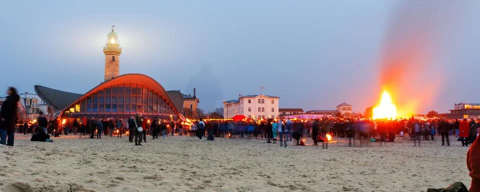 Massive Easter bonfire on sandy beach gathers crowd in Warnemunde, creating w Stock Photos