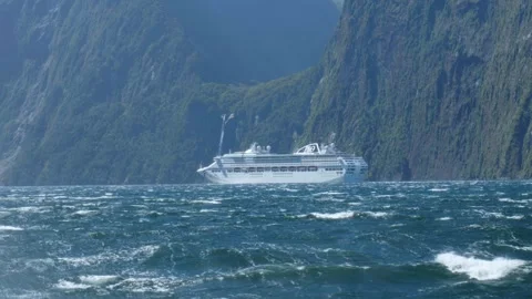 Massive ferry going past waterfall at Milford Sound Stock Footage 260368137