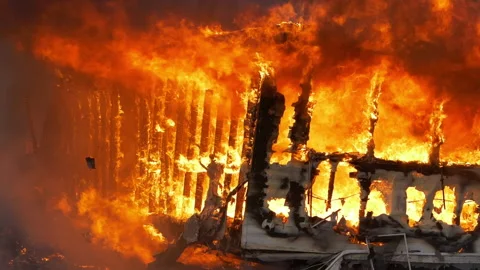 Massive flames escape from a small home that is completely engulfed in flames Stock Footage 232338877