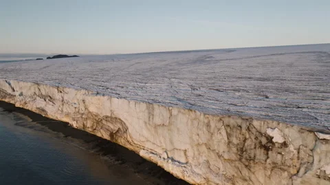 Massive glacier front above dark shoreline in Antarctica drone view Stock Footage 343122918