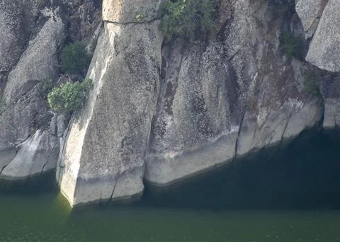Massive granite cliff face over deep green water at aldeadavila dam canyon .. Stock-Fotos