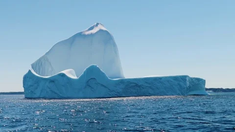 Massive ice berg floating off the coast in a cold sea Stock Footage 77890923