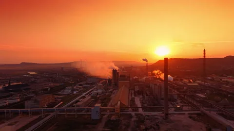 Massive industrial factory complex bathed in the warm golden light of setting Stock Footage 344602687