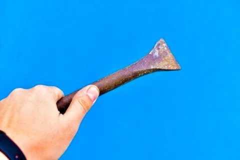 A massive iron chisel in his hand on a blue background Stock Photos