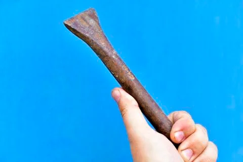A massive iron chisel in his hand on a blue background Stock Photos
