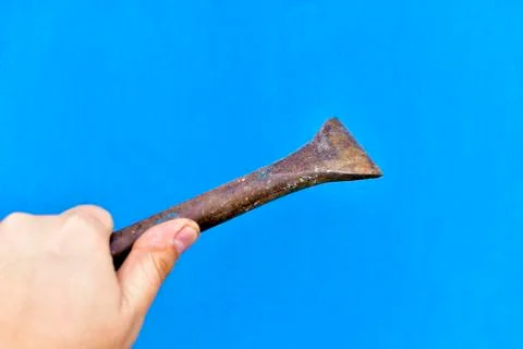 A massive iron chisel in his hand on a blue background 写真素材