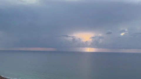 Massive Lightning Bolt Lights up Storm Clouds over the Ocean during Thunderstorm Stock Footage 261643356