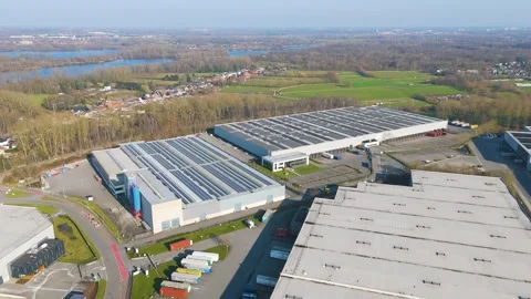 Massive logistics facility solar roofs loading docks bordered by fields forested Vidéo 329078866