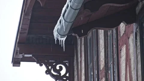 Massive Long Dangerous Icicle Hanging from Frozen Rain Gutter Posing Hazard Stock Footage 331850701