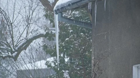 Massive Long Dangerous Icicle Hanging from Frozen Rain Gutter Posing Hazard Stock Footage 331858119
