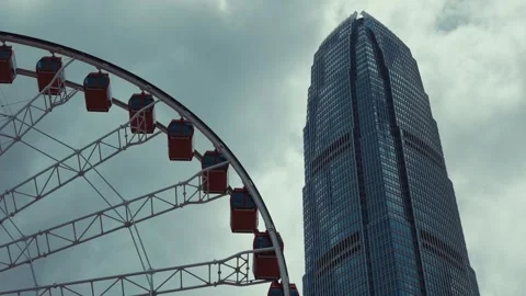 A massive modern observation wheel positioned next to a tall skyscraper in Hong 库存影片 338311375