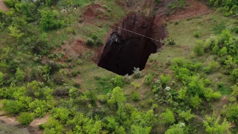 Massive natural pit in the forest with a tightrope stretched over the abyss, 4k Stock Footage 133557585