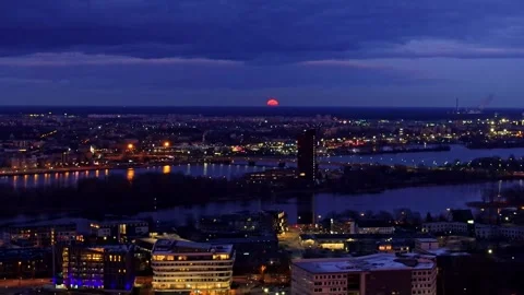Massive Orange Full Moon Rises Over Riga Skyline During Lunar Eclipse, Left Pan Video stock 308728687