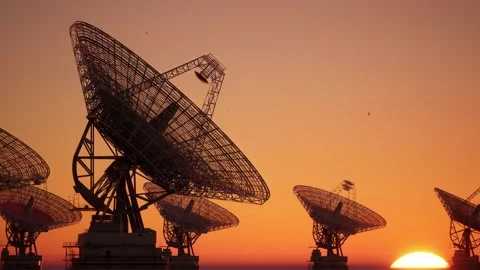 Massive Radio Telescope Array Silhouetted Against Orange Sunset Sky Stockbeeldmateriaal 339071742