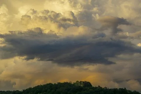 Massive rain clouds forming in the blue sky over a green forest. Stock Photos