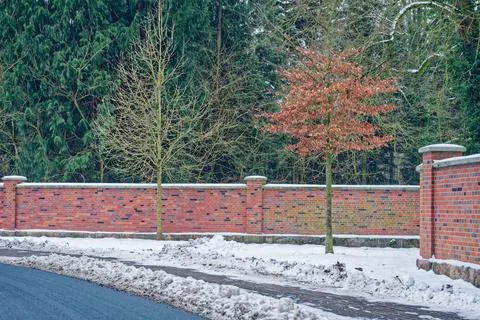 Massive red brick wall with dark inlays and snowy verge Stock Photos
