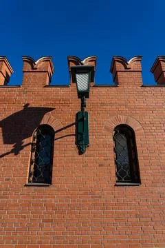 A massive, red-brick wall with small windows and a lantern Stock Photos