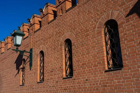 A massive, red-brick wall with small windows and a lantern Stock Photos