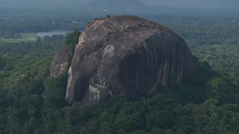 Massive rock formation surrounded by lush greenery Stock Footage 302233021
