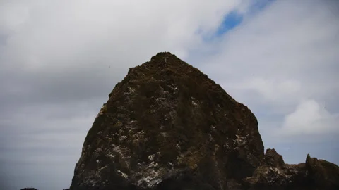 Massive sea stack beneath cloudy sky at Cannon Beach, Oregon Stock Footage 345303987