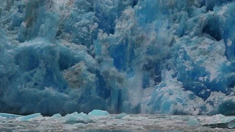 Massive sheets of bright blue ice slide off the face of South Sawyer Stock Footage