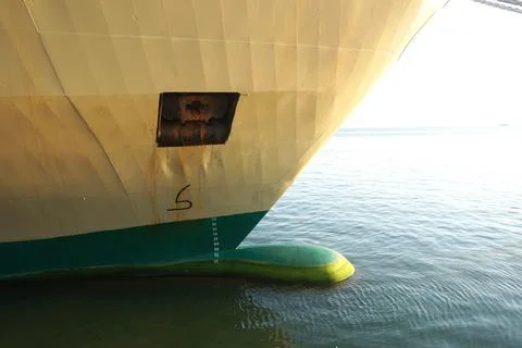 Massive ship bow cuts through calm blue water under bright sky, showcasing .. 库存照片