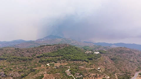 Massive smoke plume rises from forest fire burning in mountain range, with Vídeo Stock 342478374