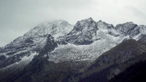 Massive snow-capped mountain peaks of alpine mountains in clouds Stock Footage 120701898