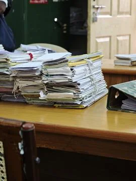 Massive stacks of old case files tied with strings sit on a wooden table in.. Foto stock