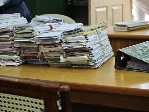 Massive stacks of old case files tied with strings sit on a wooden table in.. Foto stock